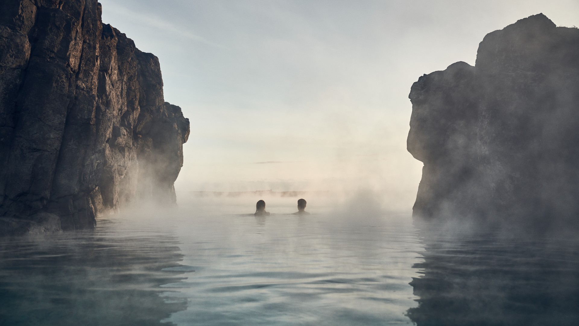 people swimming between the rocks at sky lagoon